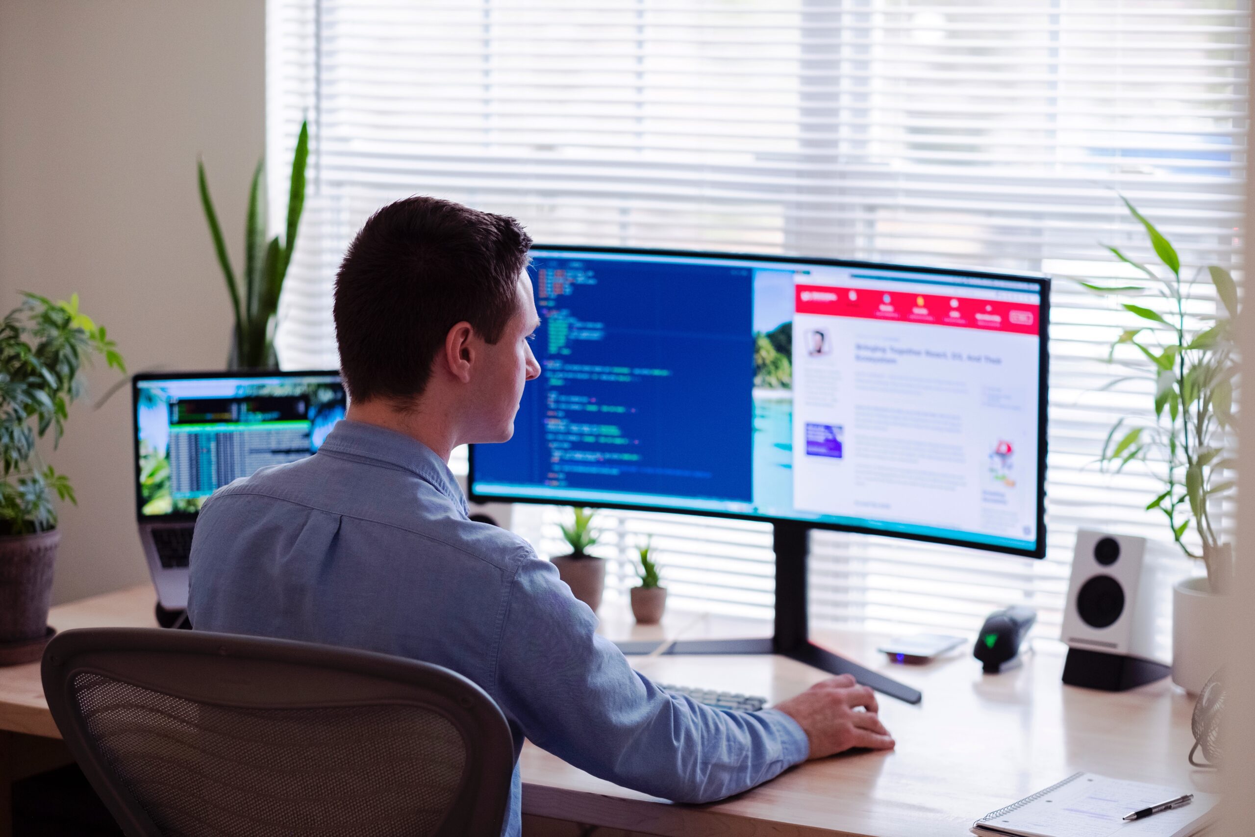 Person working at a desk in front of a montitor with various software